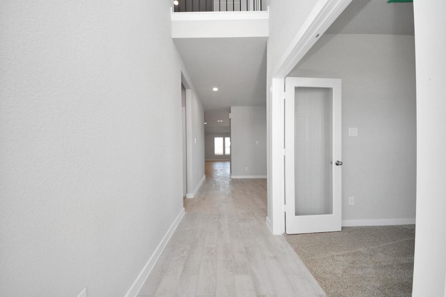 Step into elegance and sophistication in the entryway of this home, where wood-look tile flooring and high ceilings create a grand and welcoming atmosphere. The long hallway adorned with oversized baseboards offers a glimpse into the spaciousness and attention to detail found throughout the residence. Sample photo of completed home with similar floor plan. Actual colors and selections may vary. Step into elegance and sophistication in the entryway of this home, where wood-look tile flooring and high ceilings create a grand and welcoming atmosphere. The long hallway adorned with oversized baseboards offers a glimpse into the spaciousness and attention to detail found throughout the residence. Sample photo of completed home with similar floor plan. Actual colors and selections may vary.
