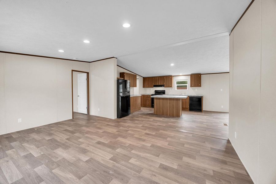 Kitchen featuring open floor plan, light wood finished floors, light countertops, black appliances, and a center island