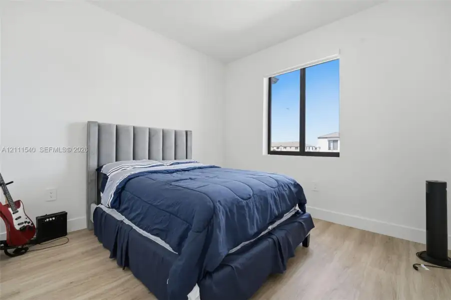 Neutral wall finish, wood-finish flooring, and a large window with black frame