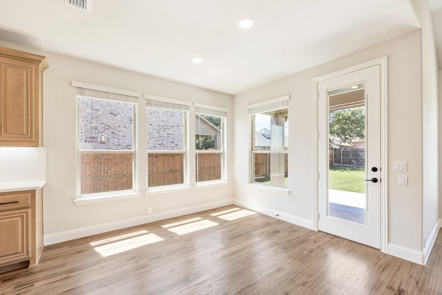 Bright breakfast nook with hardwood floors, three windows, and glass door leading to backyard Bright breakfast nook with hardwood floors, three windows, and glass door leading to backyard
