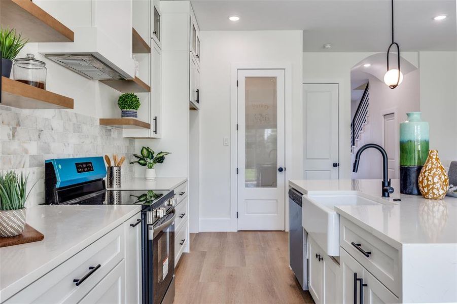 Kitchen with stainless steel appliances, open shelves, light wood-type flooring, white cabinets, and recessed lighting Kitchen with stainless steel appliances, open shelves, light wood-type flooring, white cabinets, and recessed lighting