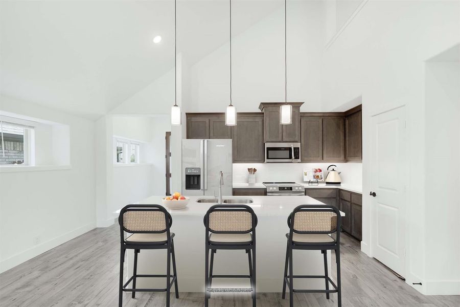 Kitchen with dark wood cabinets, white island with three bar stools, pendant lights, and vaulted ceiling Kitchen with dark wood cabinets, white island with three bar stools, pendant lights, and vaulted ceiling