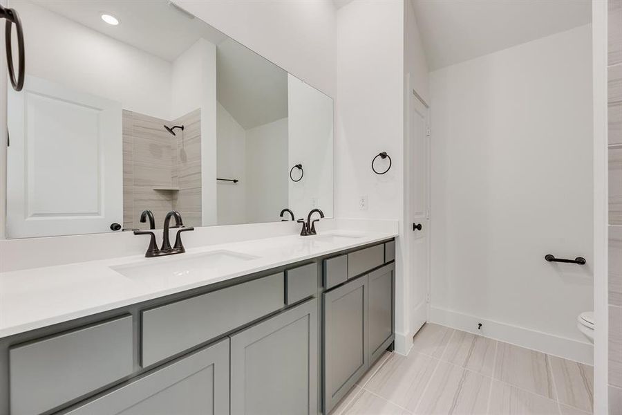Bathroom featuring double vanity, light tile patterned flooring, and a shower