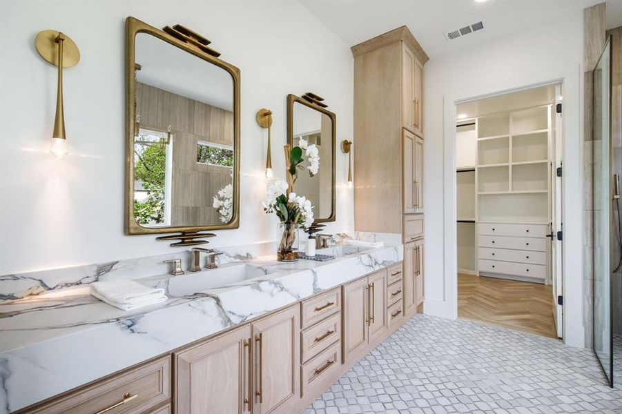 Dual vanity with integrated sinks, brass-framed mirrors, and wall sconces Dual vanity with integrated sinks, brass-framed mirrors, and wall sconces