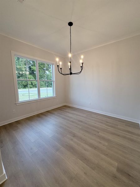 Wood-finish flooring with a modern black chandelier and perimeter crown molding Wood-finish flooring with a modern black chandelier and perimeter crown molding