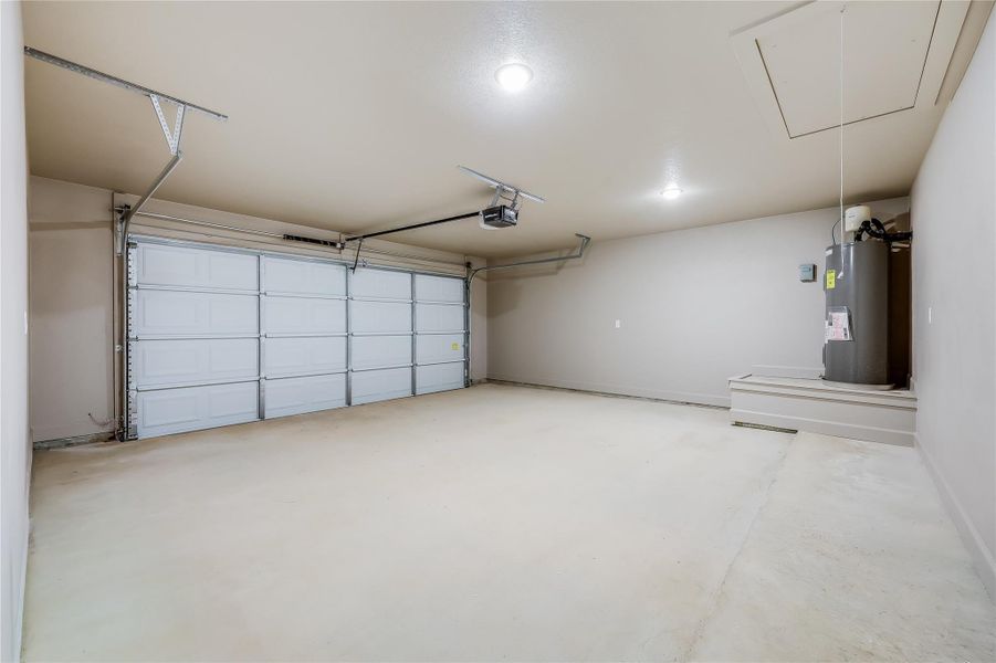 Garage featuring water heater and a garage door opener. Spacious for all your toys Garage featuring water heater and a garage door opener. Spacious for all your toys