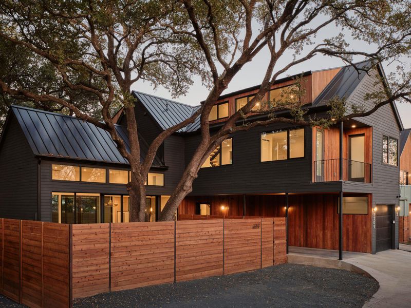 View of front of property featuring concrete driveway, an attached garage, a balcony, and a standing seam roof