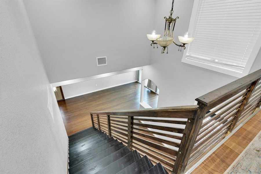 Staircase featuring wood finished floors and a chandelier