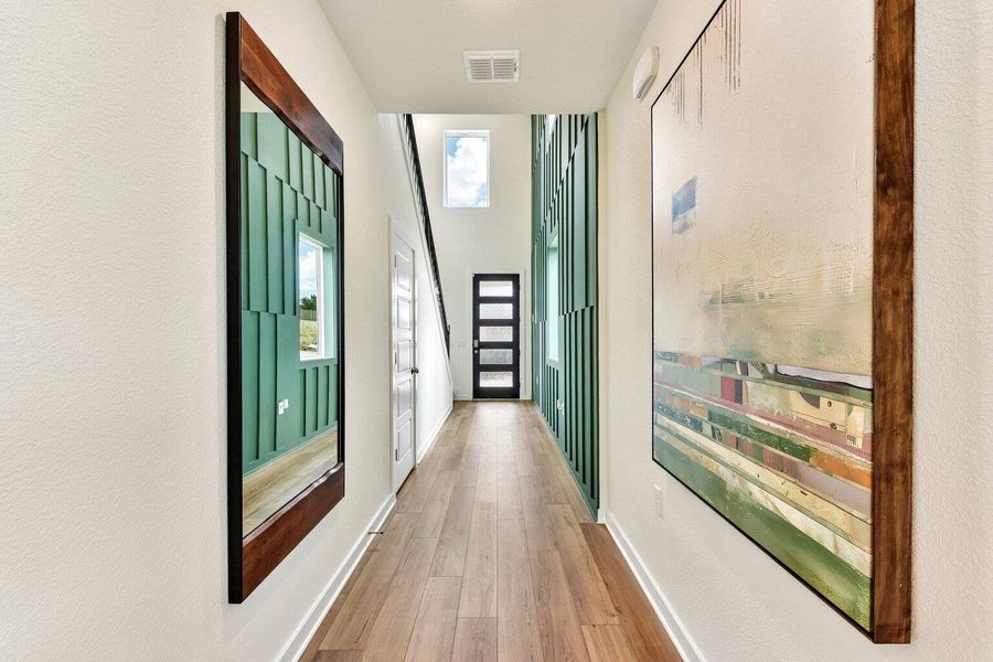 An inviting hallway showcases rich wood-look flooring and soaring, panel-detailed vertical walls. An inviting hallway showcases rich wood-look flooring and soaring, panel-detailed vertical walls.