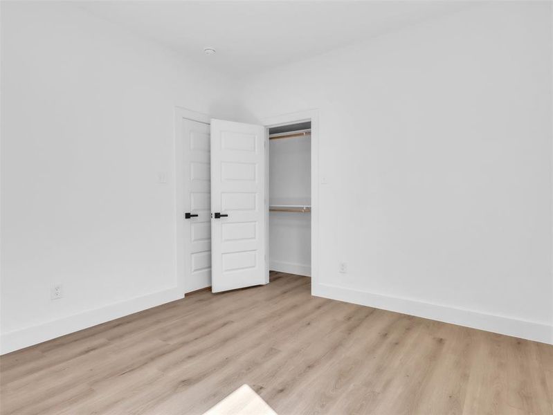 Unfurnished bedroom with baseboards, wood finished floors, and a closet Unfurnished bedroom with baseboards, wood finished floors, and a closet