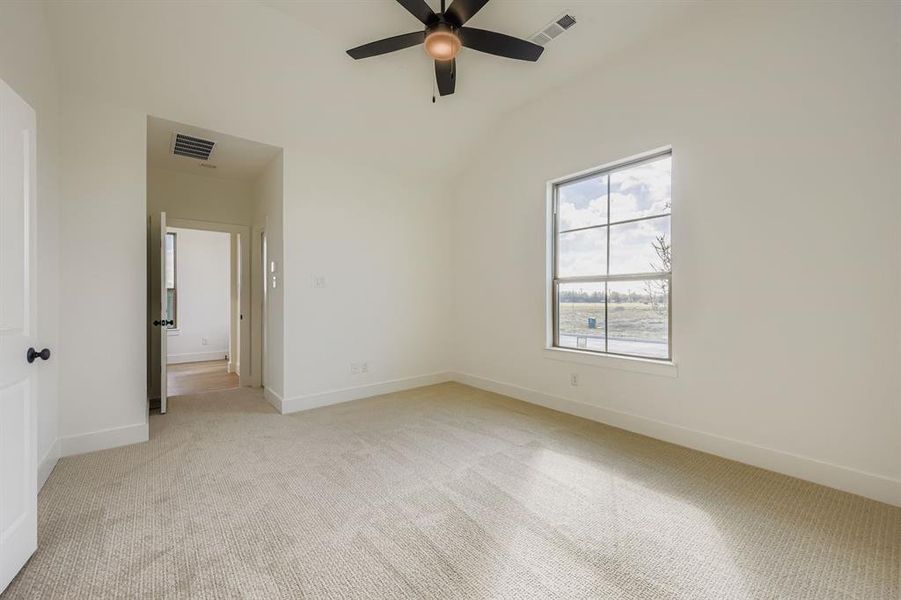 Empty room with light colored carpet, lofted ceiling, and a ceiling fan Empty room with light colored carpet, lofted ceiling, and a ceiling fan