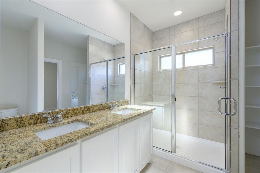 Bathroom featuring tile patterned flooring, vanity, toilet, and a shower with shower door