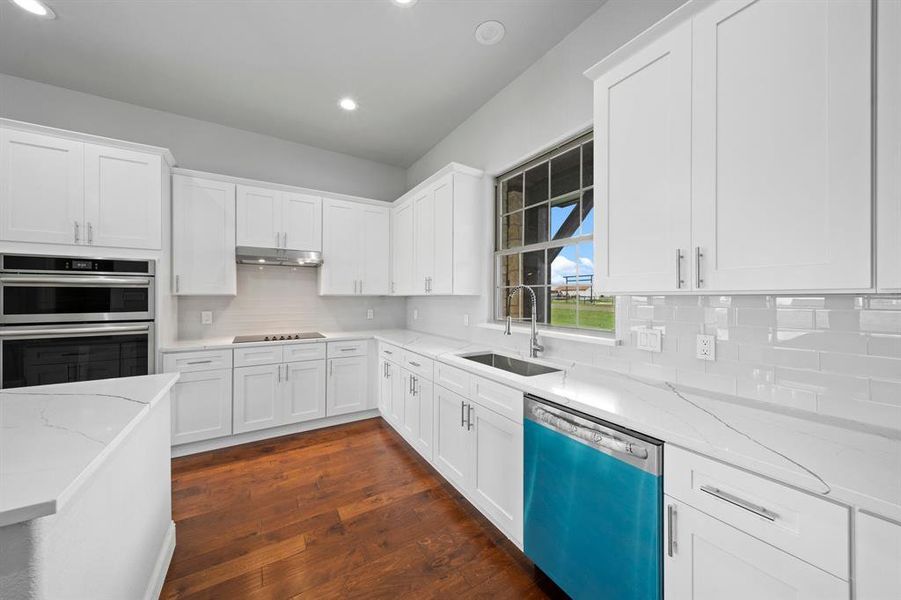 Kitchen featuring dark wood-type flooring, tasteful backsplash, appliances with stainless steel finishes, and sink