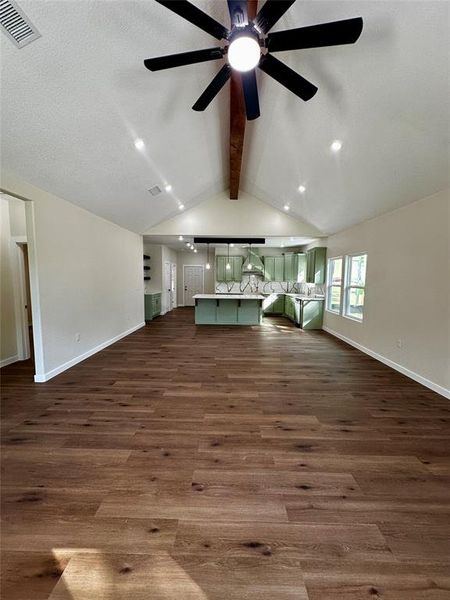 Vaulted ceiling with an exposed wood beam, recessed lighting, and a ceiling fan