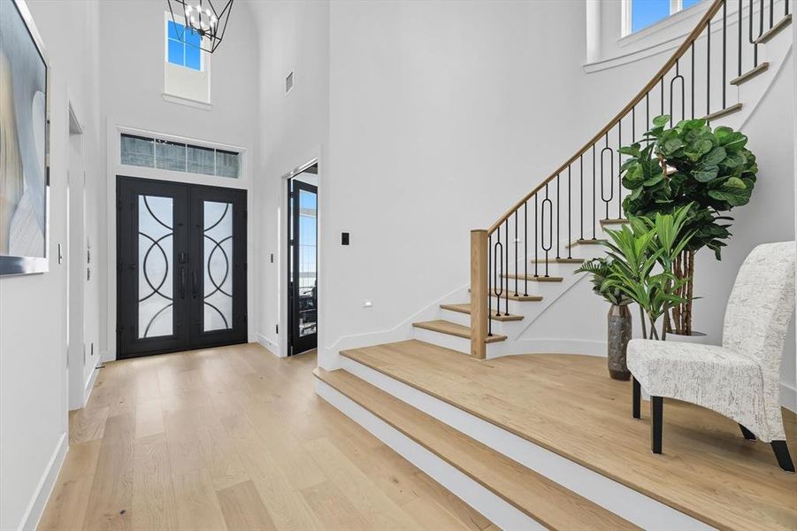Foyer with light hardwood floors, a high ceiling, stairway, and french doors Foyer with light hardwood floors, a high ceiling, stairway, and french doors