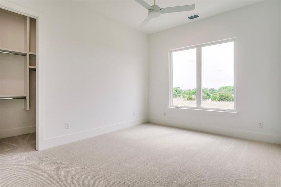 Unfurnished bedroom with baseboards, visible vents, a spacious closet, and light colored carpet