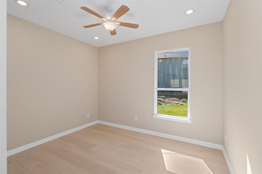 Bright secondary bedroom with large window and ceiling fan. Comfort, light, and style combine effortlessly.