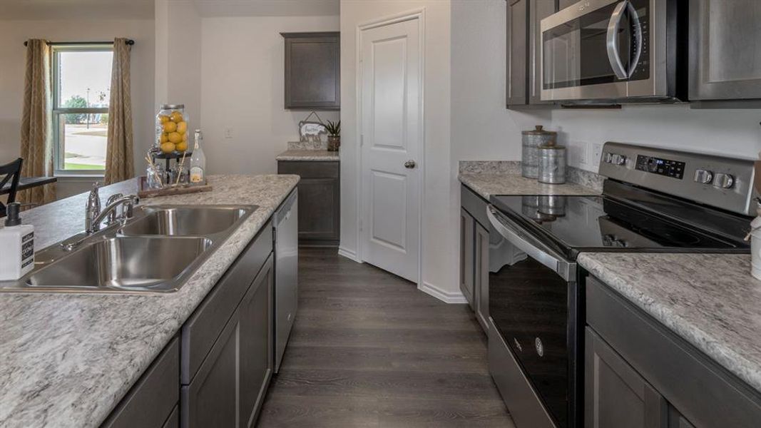 Kitchen with stainless steel appliances, light countertops, and dark wood finished floors