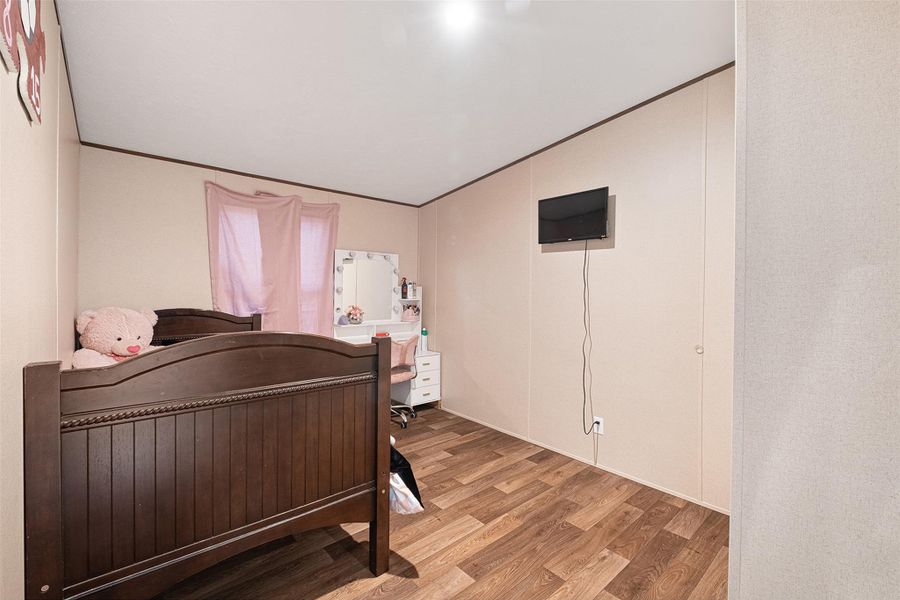Bedroom featuring wood finished floors, crown molding, and a desk