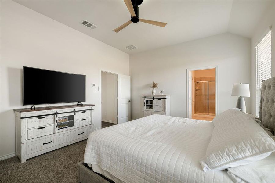 Bedroom with carpet flooring, vaulted ceiling, a ceiling fan, and connected bathroom Bedroom with carpet flooring, vaulted ceiling, a ceiling fan, and connected bathroom