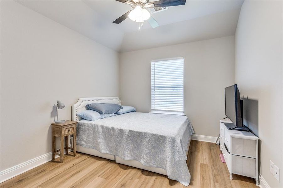 Bedroom with light wood finished floors, a ceiling fan, and vaulted ceiling Bedroom with light wood finished floors, a ceiling fan, and vaulted ceiling