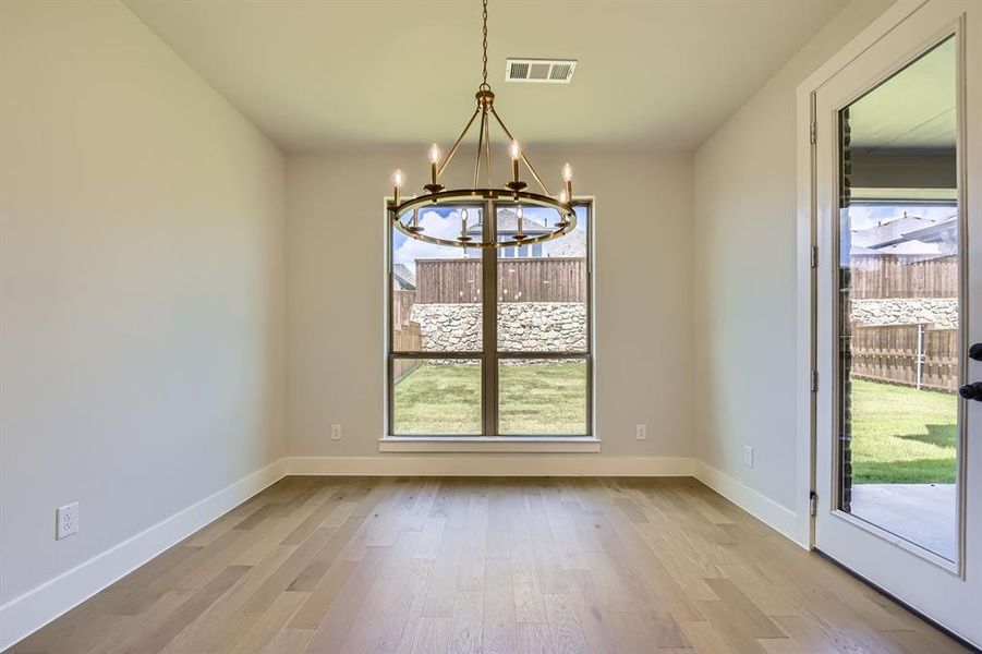 Unfurnished dining area featuring a chandelier and wood finished floors Unfurnished dining area featuring a chandelier and wood finished floors