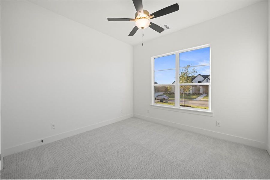 Interior room featuring a large window, light gray carpeting, and a ceiling fan with integrated lighting