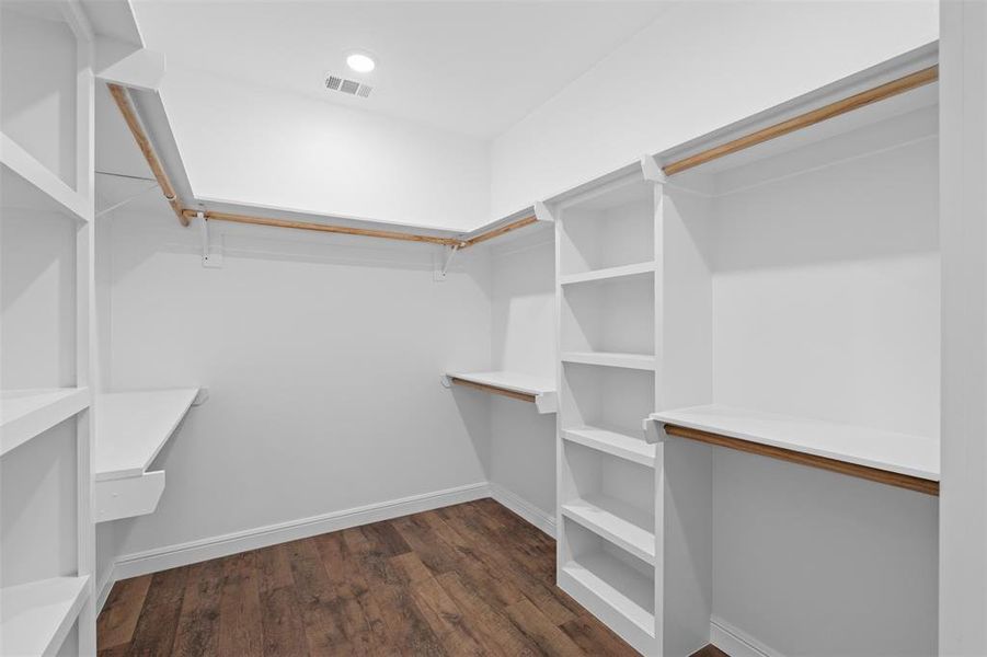 Walk in closet with dark wood finished floors