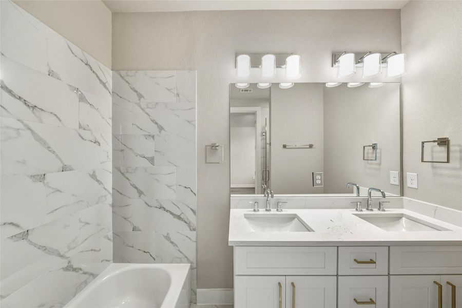 Experience luxury in this master bathroom, featuring elegant marble tiles, a sleek double vanity, and modern lighting for a spa-like retreat.