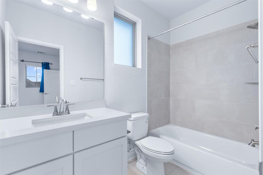 Full bath featuring washtub / shower combination, vanity, and light tile patterned floors