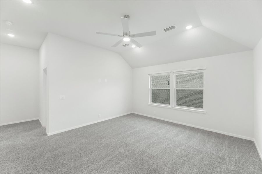 Empty bedroom with vaulted ceiling, ceiling fan, gray carpet, and single window