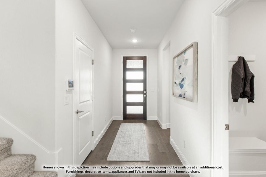 Entryway hallway with dark wood front door, hardwood floors, white walls, and coat hooks near stairs Entryway hallway with dark wood front door, hardwood floors, white walls, and coat hooks near stairs