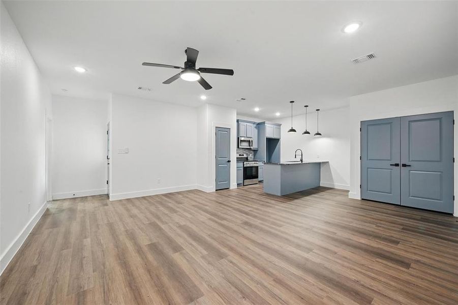 Unfurnished living room featuring recessed lighting, visible vents, ceiling fan, a sink, and wood finished floors