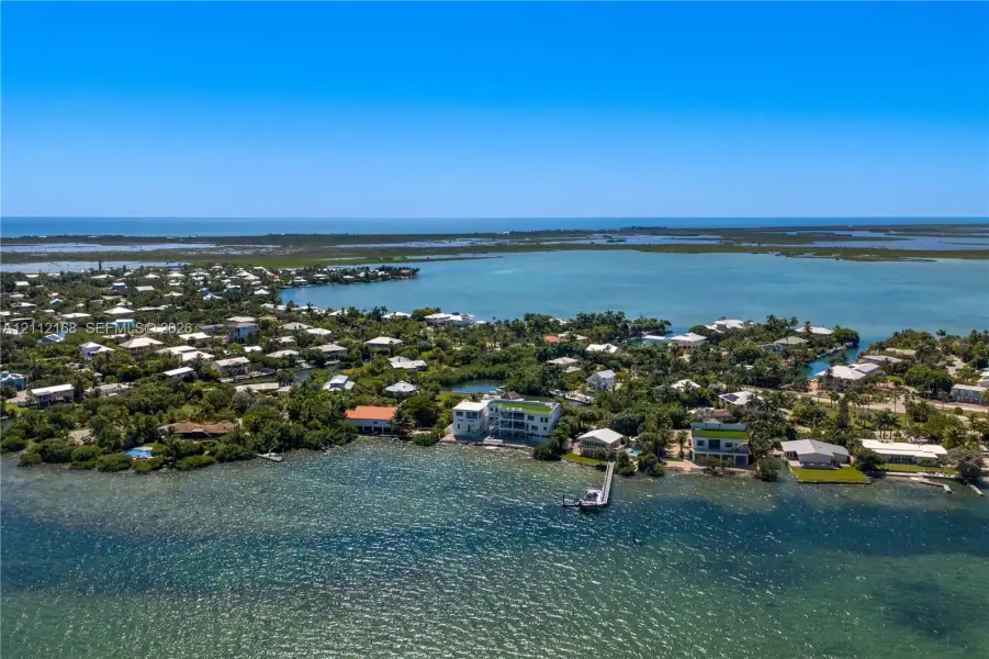 Aerial perspective of coastal property featuring direct water frontage, a private deep-water dock, and tropical vegetation within a waterfront setting Aerial perspective of coastal property featuring direct water frontage, a private deep-water dock, and tropical vegetation within a waterfront setting