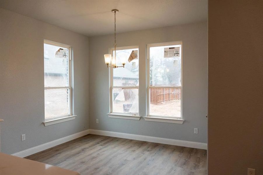 Unfurnished dining area with a chandelier, light hardwood / wood-style flooring, and a wealth of natural light