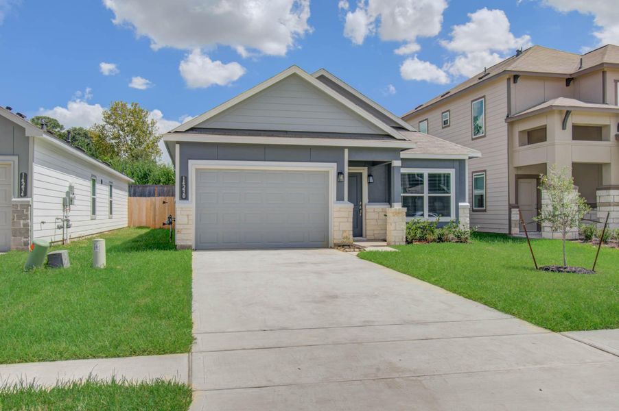 Charming single-story home with a modern facade, featuring a spacious two-car garage and a well-maintained front lawn.