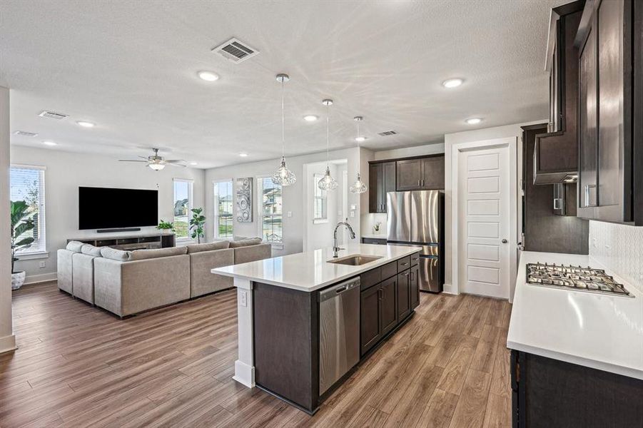 Kitchen featuring, smokey grey cabinets,  island with single basin sink, and appliances with stainless steel finishes