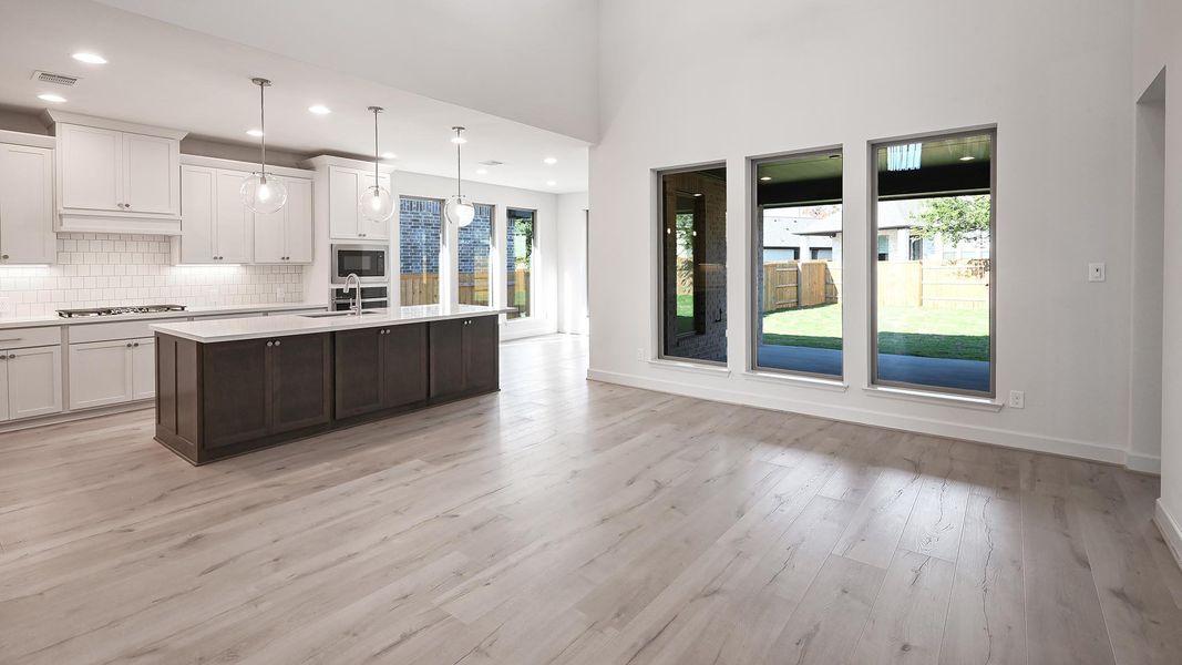 Kitchen featuring white cabinetry, backsplash, pendant lighting, a kitchen island with sink, and dark brown cabinets Kitchen featuring white cabinetry, backsplash, pendant lighting, a kitchen island with sink, and dark brown cabinets