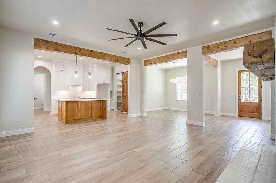 Kitchen featuring open floor plan, light wood-style flooring, white cabinets, a ceiling fan, and light countertops Kitchen featuring open floor plan, light wood-style flooring, white cabinets, a ceiling fan, and light countertops