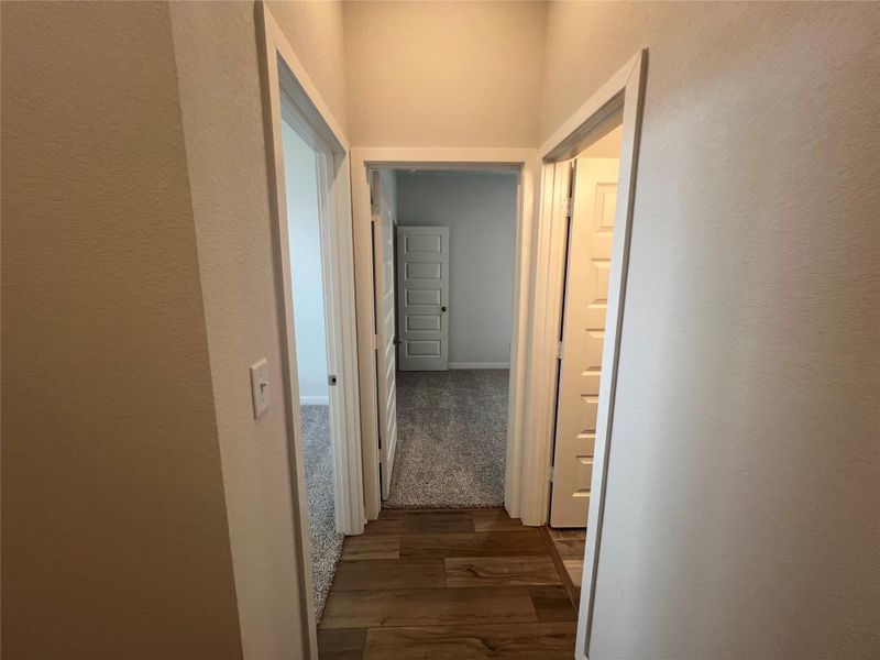 A well-lit hallway with two separate doorways leads to inviting interior spaces.