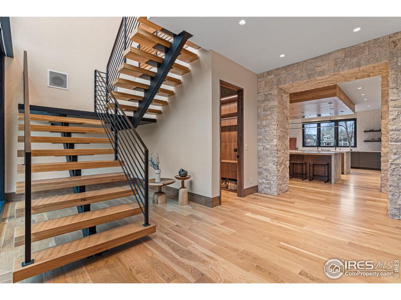 A grand 26-foot high foyer features a majestic white oak ceiling and mono-stair floating staircase with solid white oak treads and artisan crafted ironwork railings. The second level can also be accessed by the elevator.