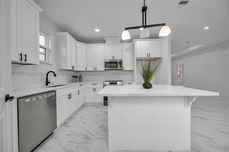 Kitchen featuring white cabinetry, appliances with stainless steel finishes, and a kitchen island