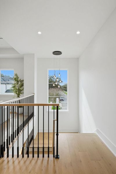 The staircase serves as a bright, aesthetic transition between levels. As you reach the turn, you are greeted by a dramatic multi-pendant "raindrop" chandelier.