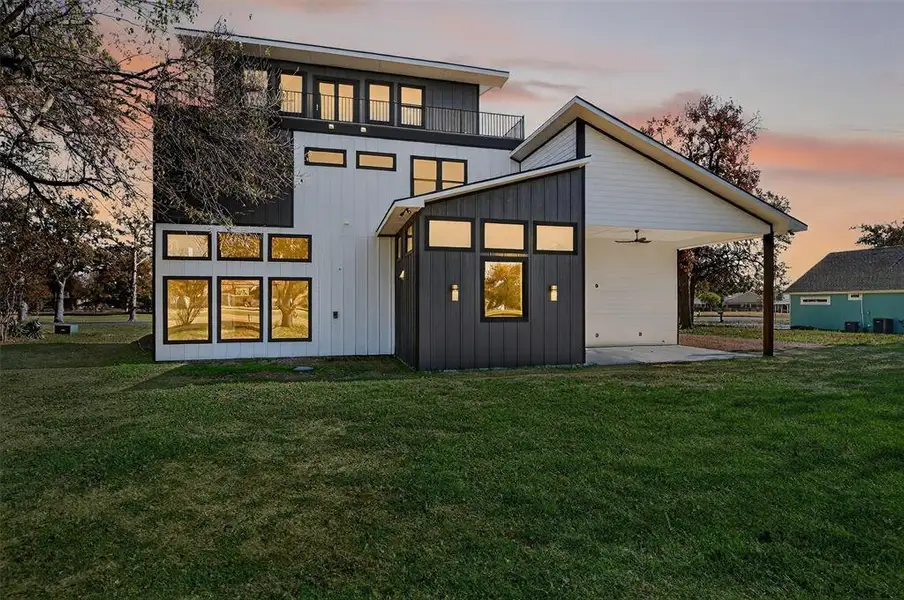 Back of property with a lawn, ceiling fan, a patio, and board and batten siding