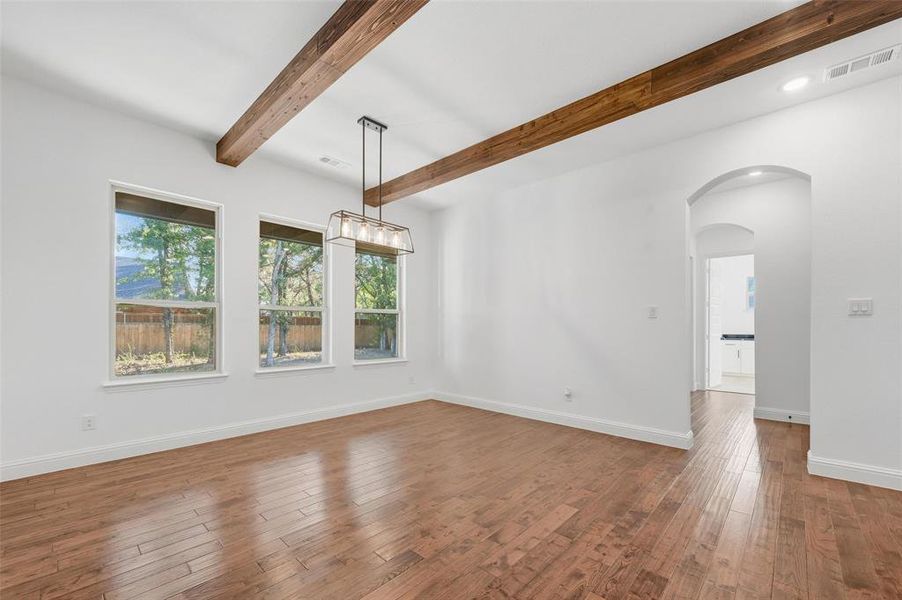Unfurnished room with arched walkways, beam ceiling, dark wood finished floors, and recessed lighting