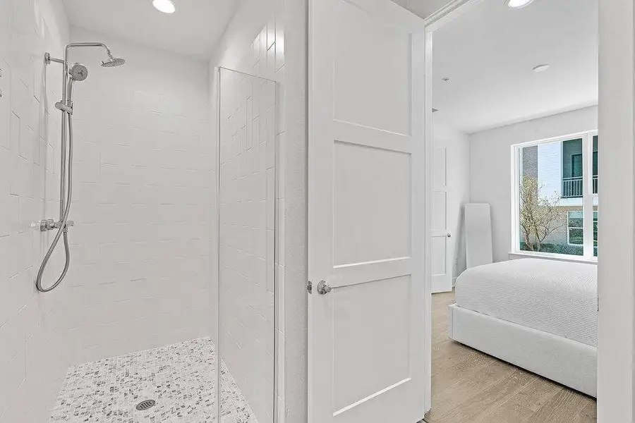 Ensuite bathroom featuring tiled shower, light wood-type flooring, and recessed lighting