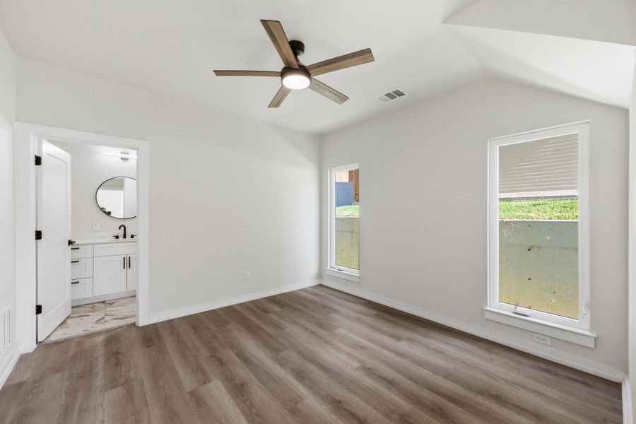 Unfurnished bedroom with a ceiling fan, light wood-style flooring, and ensuite bathroom