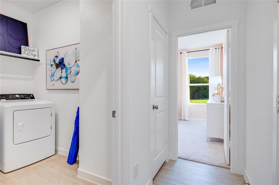 Clothes washing area featuring light wood-style flooring, laundry area, visible vents, baseboards, and washer / clothes dryer