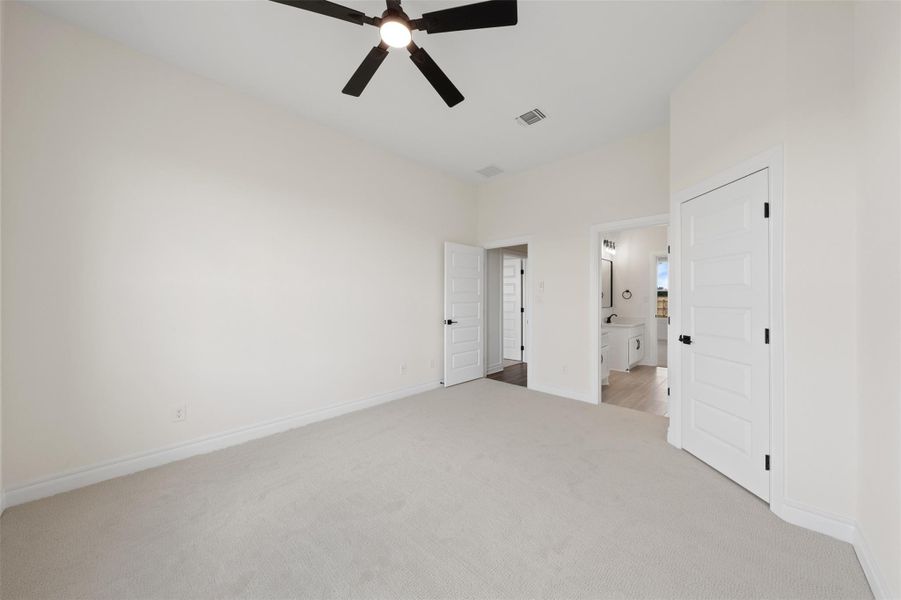 Unfurnished bedroom featuring light colored carpet, a ceiling fan, and ensuite bath Unfurnished bedroom featuring light colored carpet, a ceiling fan, and ensuite bath