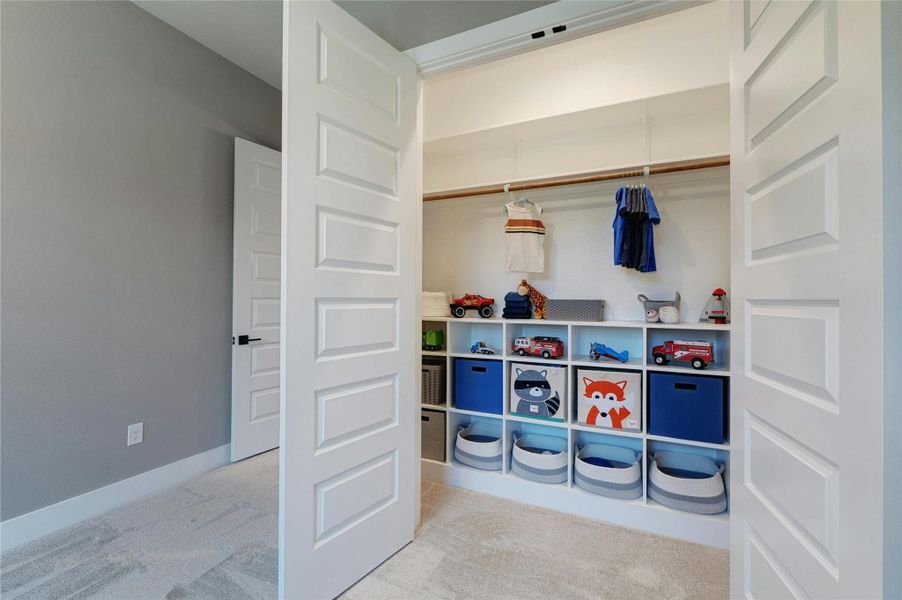 Spacious closet featuring built-in shelving, hanging rod, and light-colored carpeting